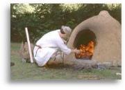 Ein Lehmofen wird zum Brotbacken angeheizt